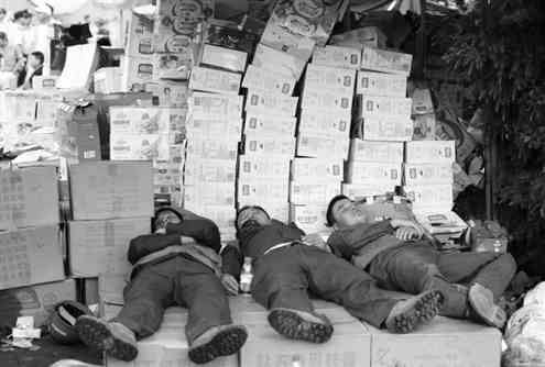 双河中学安置点，疲惫的工作人员躺在物资旁休息。